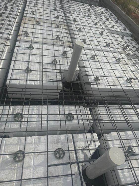 Close-up of reinforcement, spacers and pipe penetrations at slab preparation